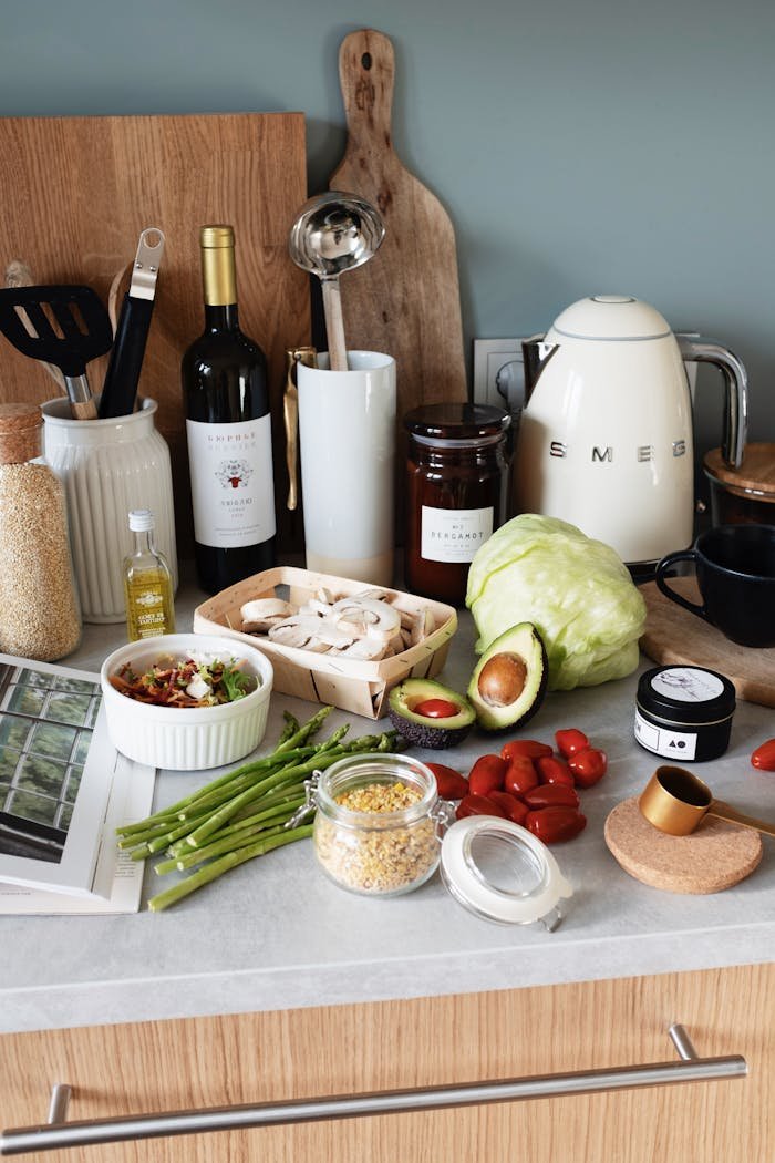 Assorted healthy food and vegetables placed on gray tabletop against kitchen utensils and appliances in cozy kitchen in apartment on sunny day